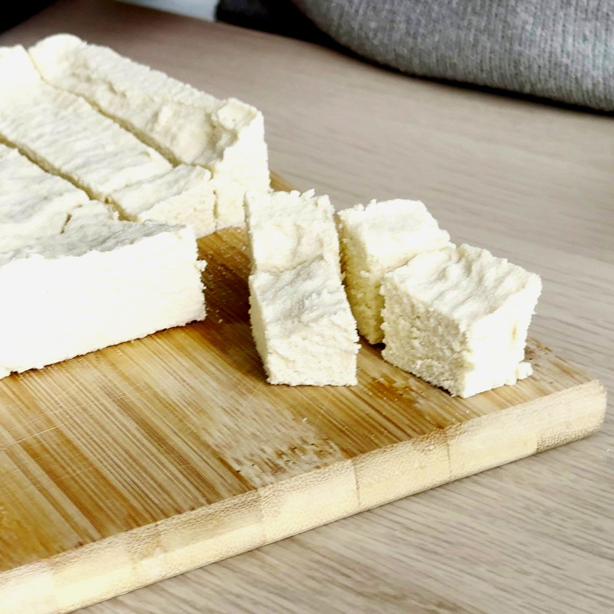 Fresh homemade plant-based cheese cut into cubes on a wooden board