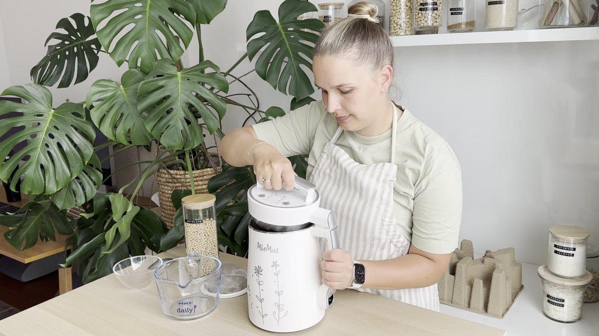 Woman making plant-based milk with MioMat in a bright kitchen
