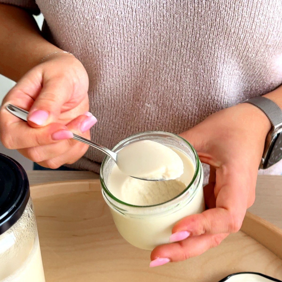 Spoon lifting thick homemade soy yogurt from the jar
